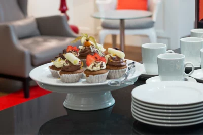 Etagere mit Schokoladen Cupcakes, daneben ein Stapel Kuchenteller und Kaffeetassen