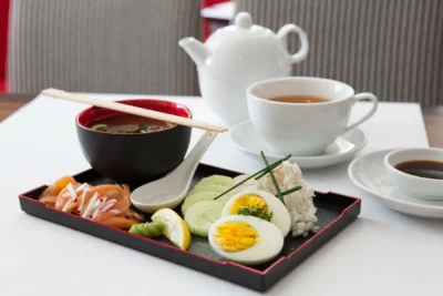 Blick auf ein Tablett mit japanischem Frühstück mit Suppe, Lachs, Ei, und Reis
