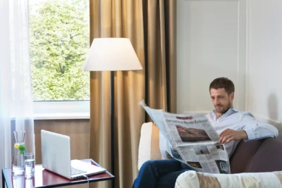 Ein Mann sitzt auf einem Sofa im Hotel Harmonie und liest eine Zeitung