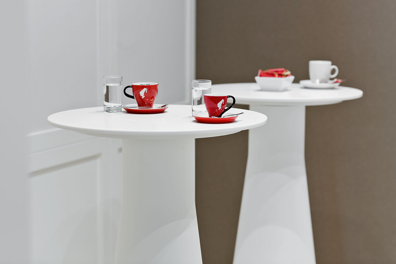 Zwei Stehtische im Seminarhotel Wien mit roten Espressotassen und Wassergläsern