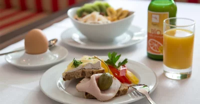 Liebevoll angerichtete Teller mit belegten Broten, Ei, Müsli und Orangensaft