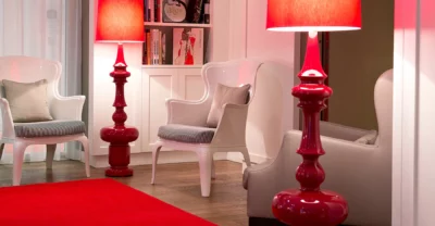 In der Lounge des Harmonie Hotels stehen zwei weiße Stühle und rote Stehlampen