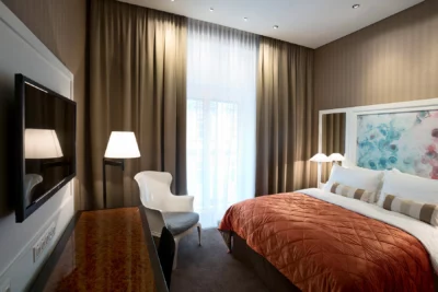 Blick in ein Hotelzimmer des Hotel Harmonie mit Doppelbett und großer Fensterfront