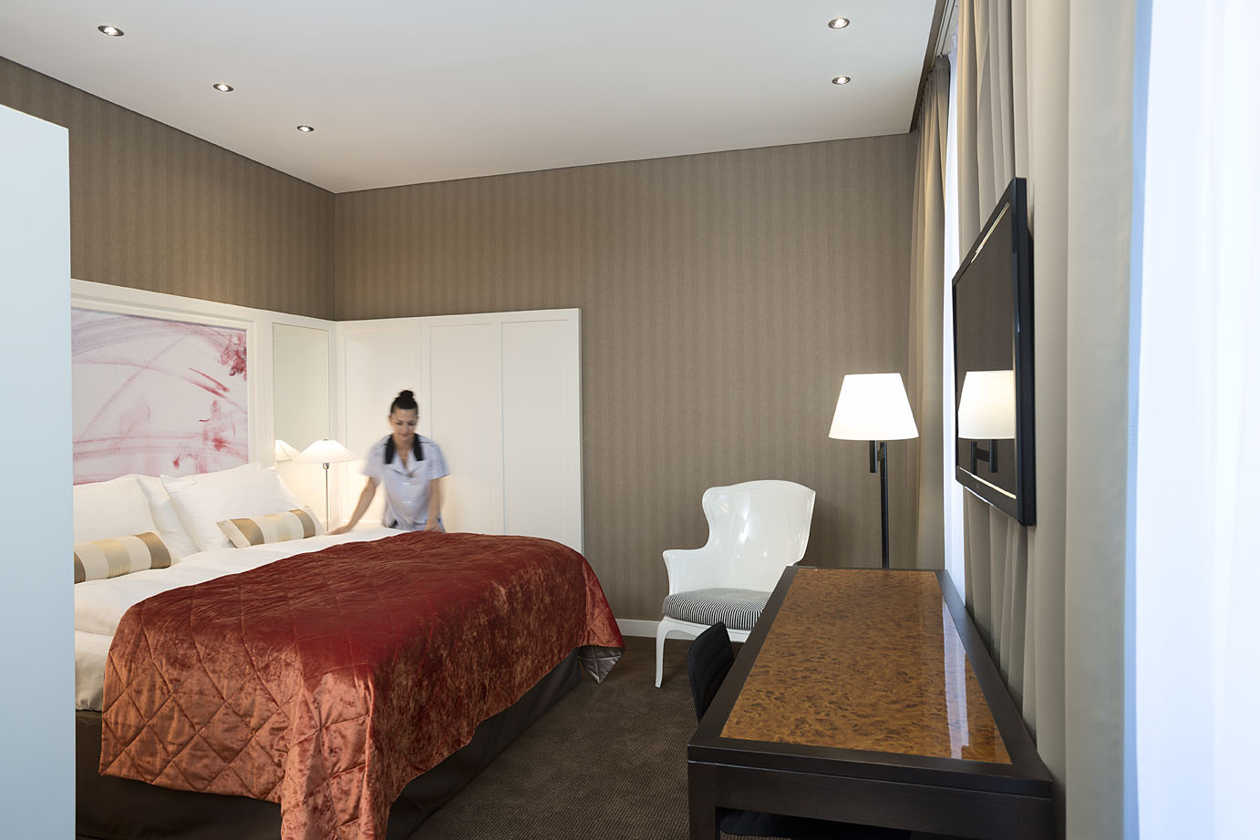 Eine Hotelmitarbeiterin richtet das Doppelbett in einem Hotelzimmer in Wien 