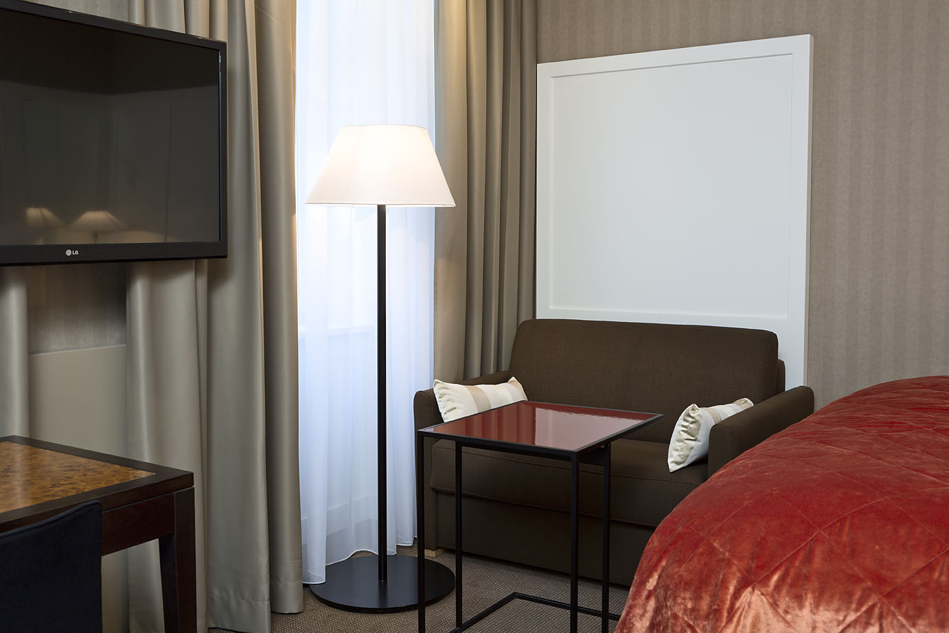 Kleines Sofa und Stehlampe in einem Zimmer des Harmonie Hotel Wien Zentrum