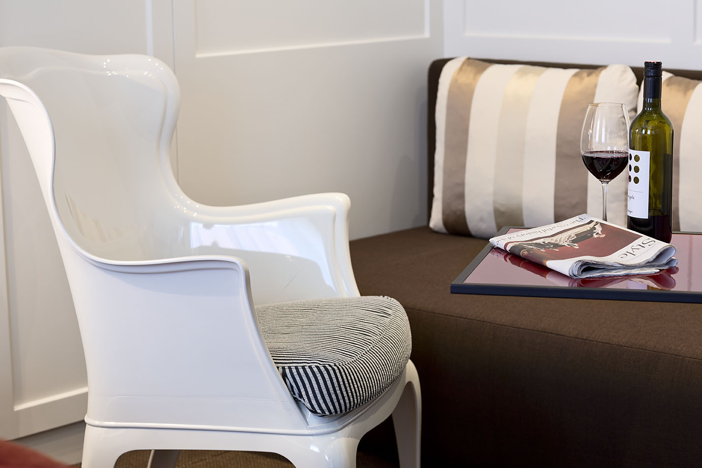 Ein weißer Stuhl steht vor einem Tisch mit Rotwein und Zeitung im Hotel Wien Zentrum