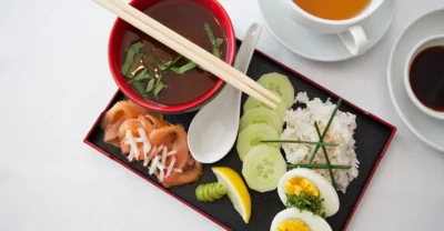 Ein Japanisches Frühstück mit Suppe, Lachs, Reis und Ei auf einem Tablett angerichtet