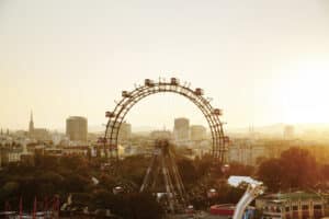 Ein Riesenrad ragt über die Häuser hervor im Dämmerschein des Sommerabendlichts.